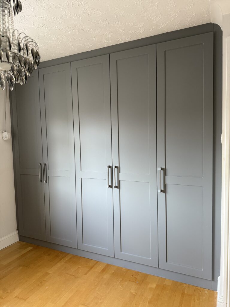 Completed floor-to-ceiling fitted wardrobe with grey shaker doors and metal handles