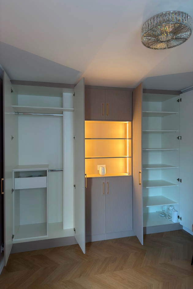 Interior of bespoke fitted wardrobe with hanging rails, adjustable shelving, internal drawers and illuminated LED shelving